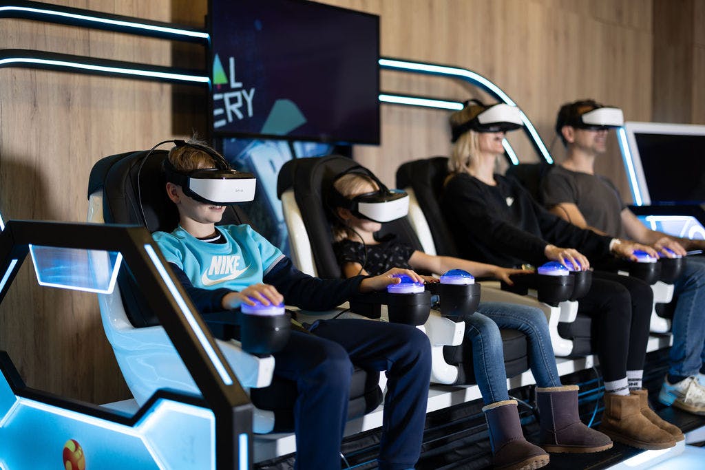 Familie sitzt im VR Theater und sieht sich mit VR Brillen Film an. 