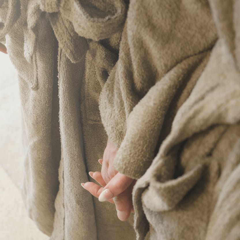 Zwei Personen in flauschigen Bademänteln halten sich an den Händen