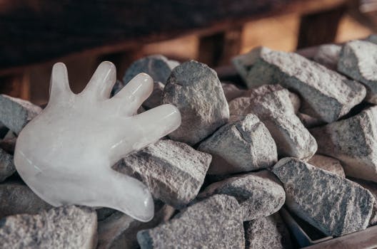 Eine Hand aus Eis auf heißen Steinen in der Sauna.