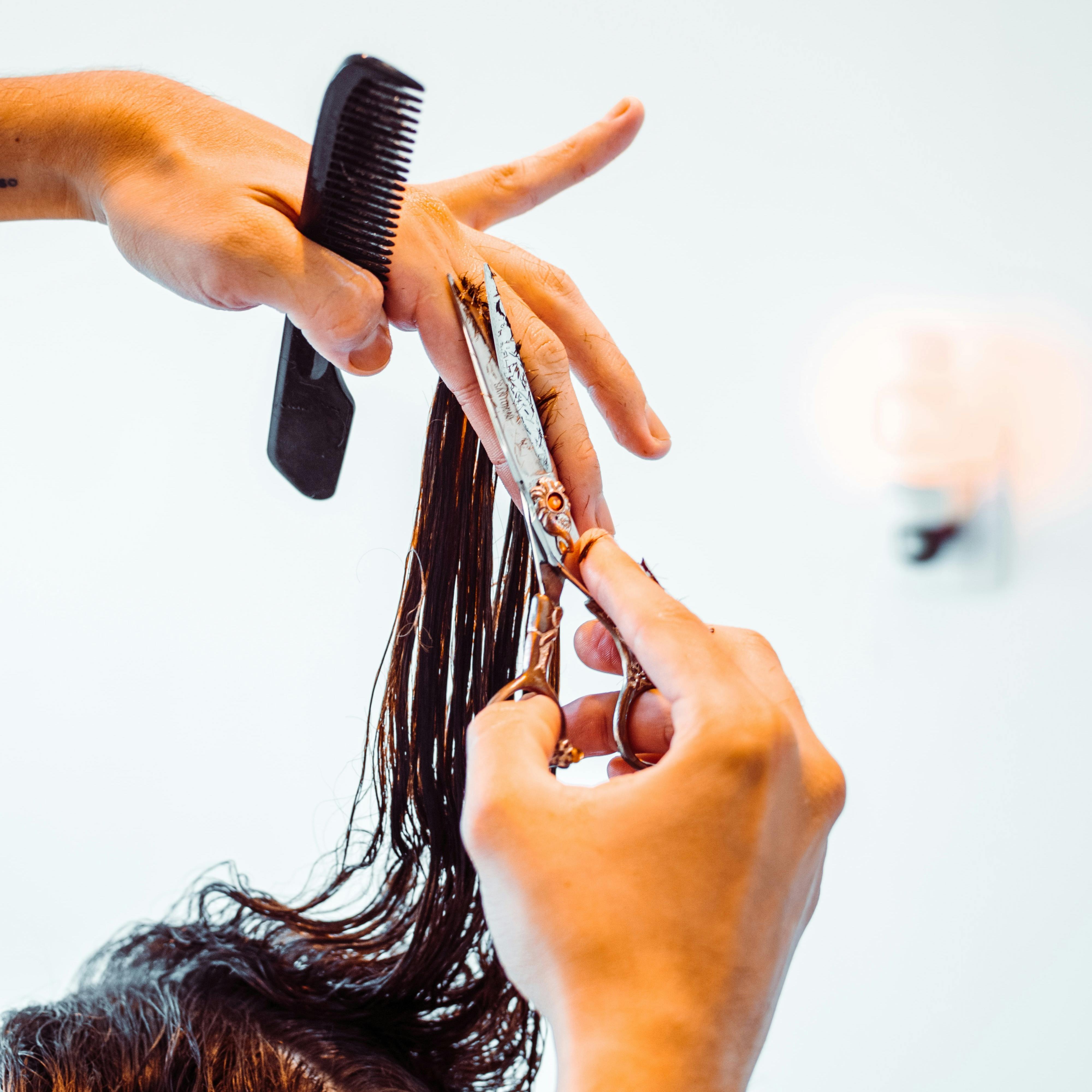 Friseur der einem Gast die Haare schneidet. 