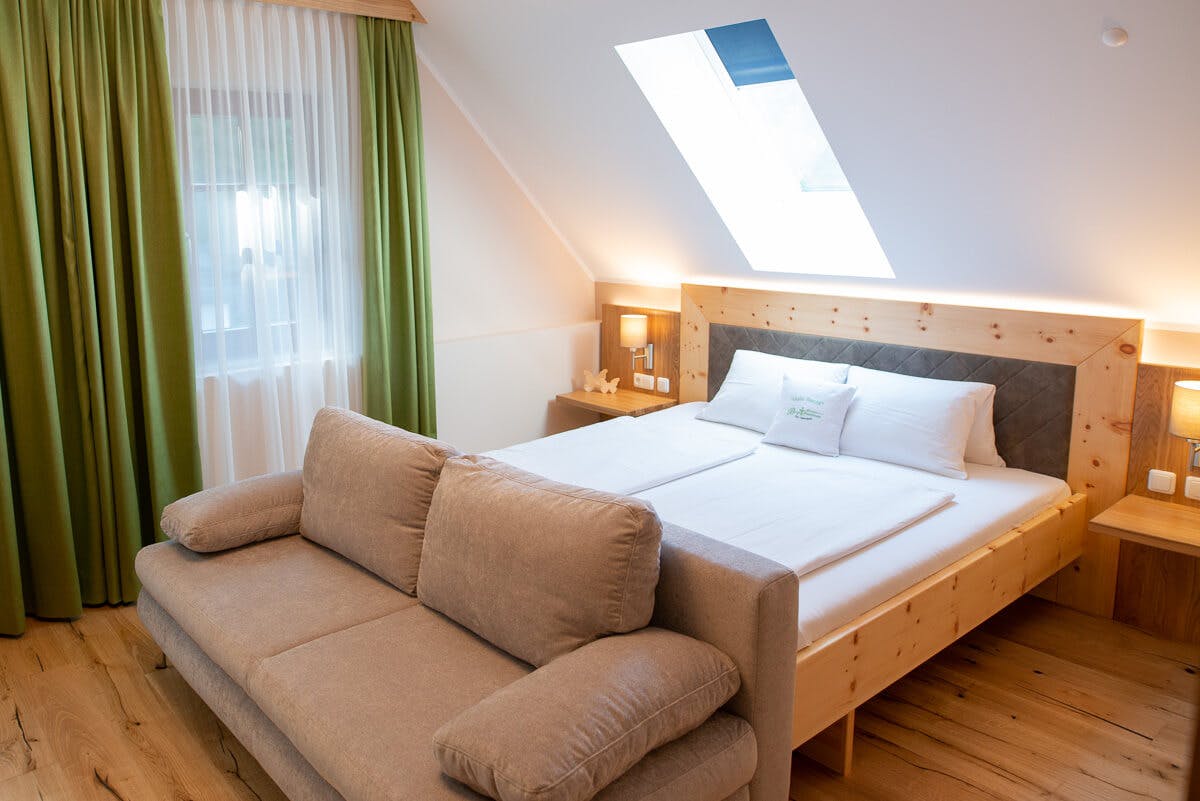 Ein helles Doppelzimmer mit Sofa im Gästehaus Bergbrunnen.