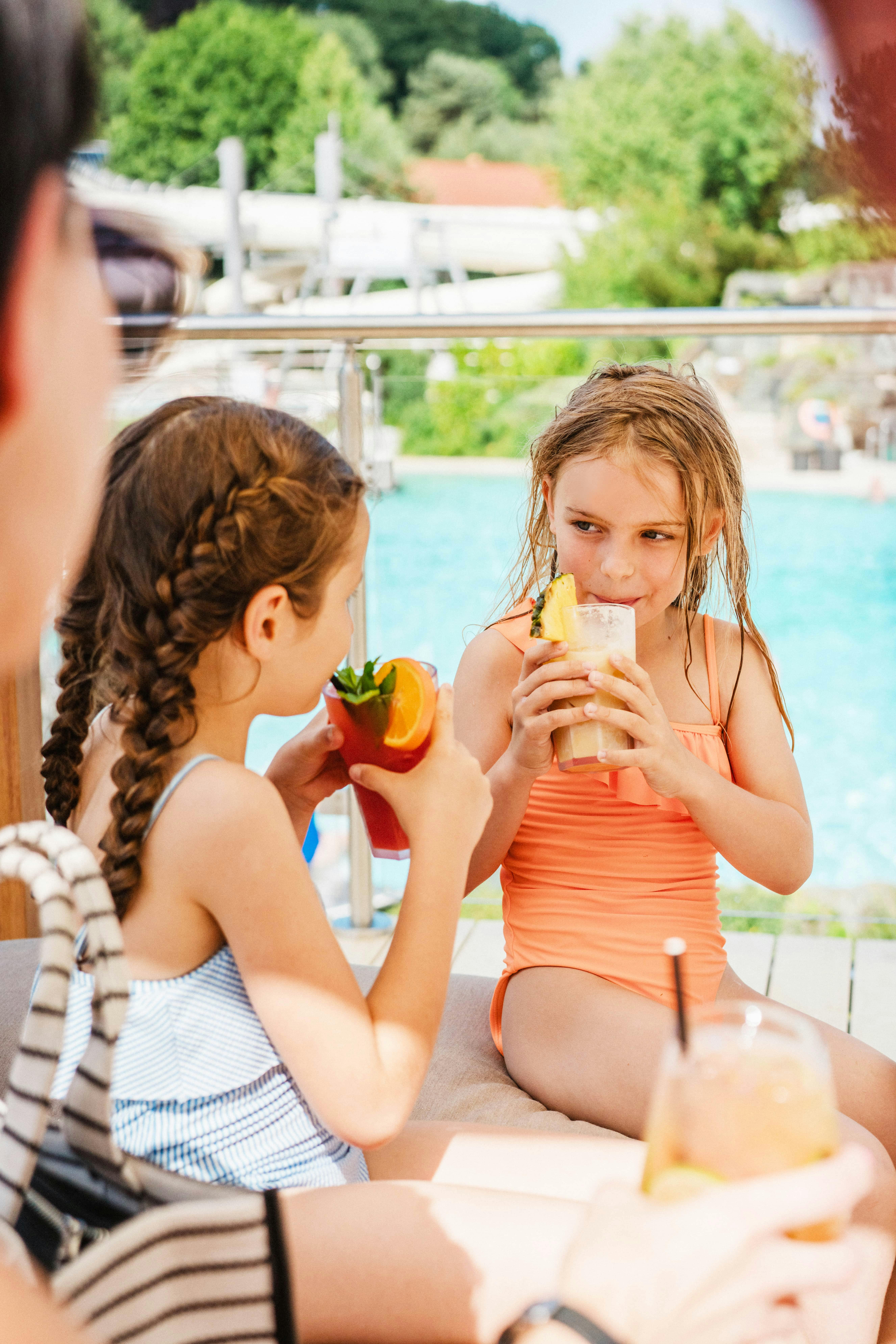 Two girls in swimwear drink colorful cocktails on the rooftop lounge at the Loipersdorf thermal spa.