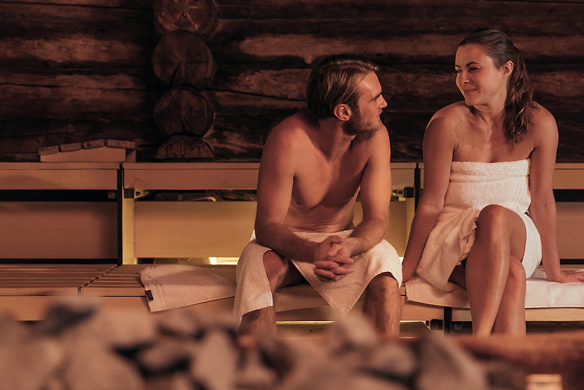 Paar sitzt in der Sauna und blickt sich an