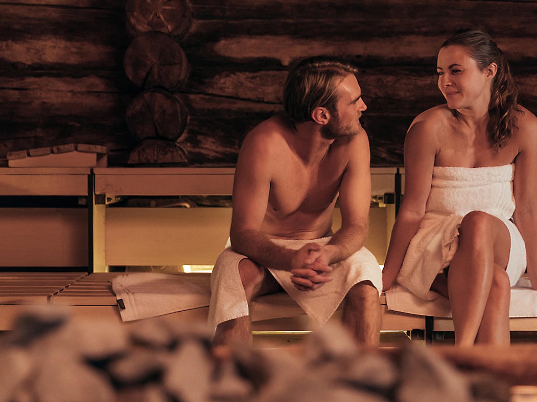 Paar sitzt in der Sauna und blickt sich an