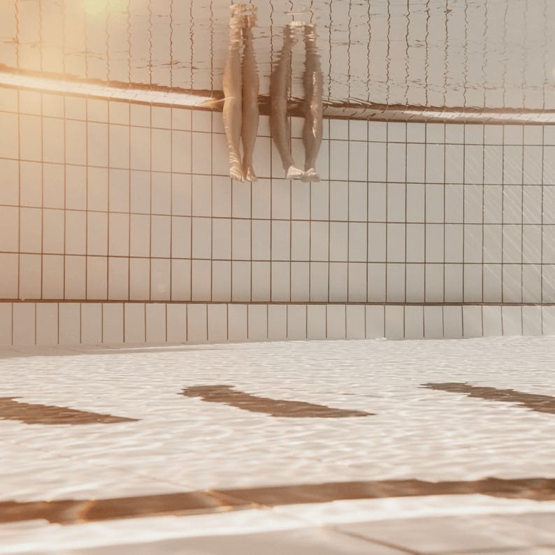 Two people are dipping their legs in the water.