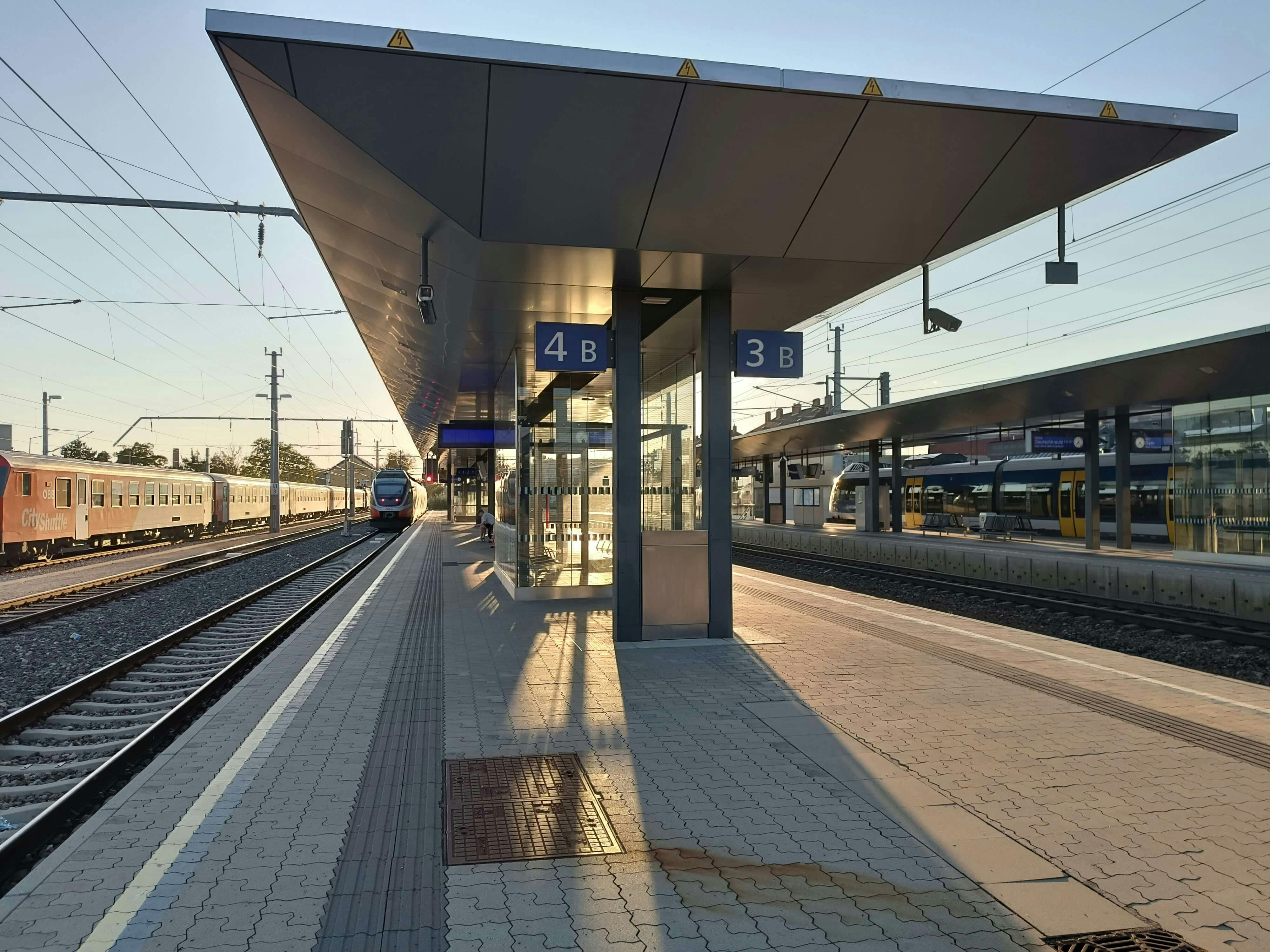 Ansicht eines Bahnsteiges mit einfahrenen Zug in den Bahnhof. 