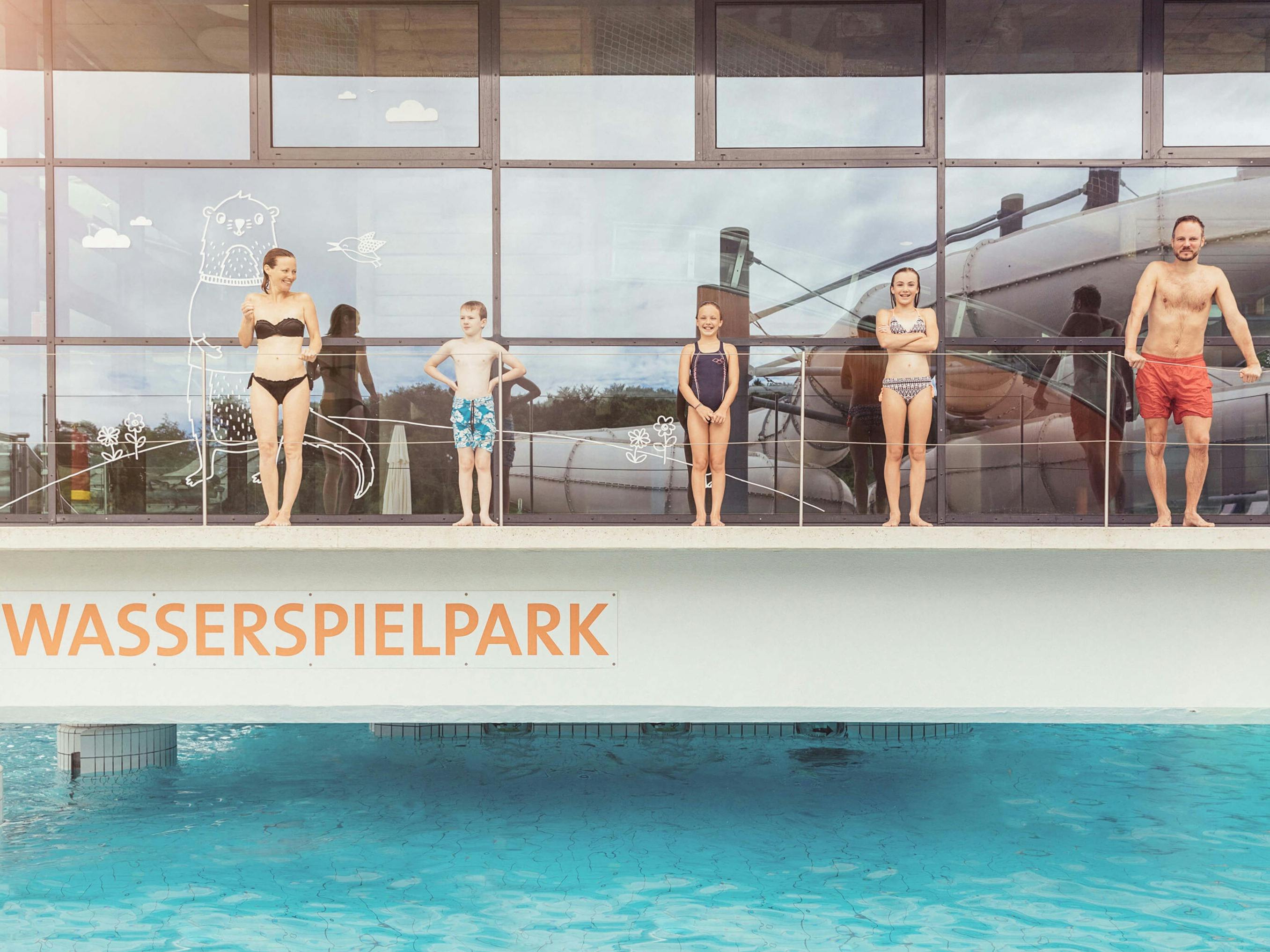 Familie steht auf Erhöhung vor dem Wasserspielpark.
