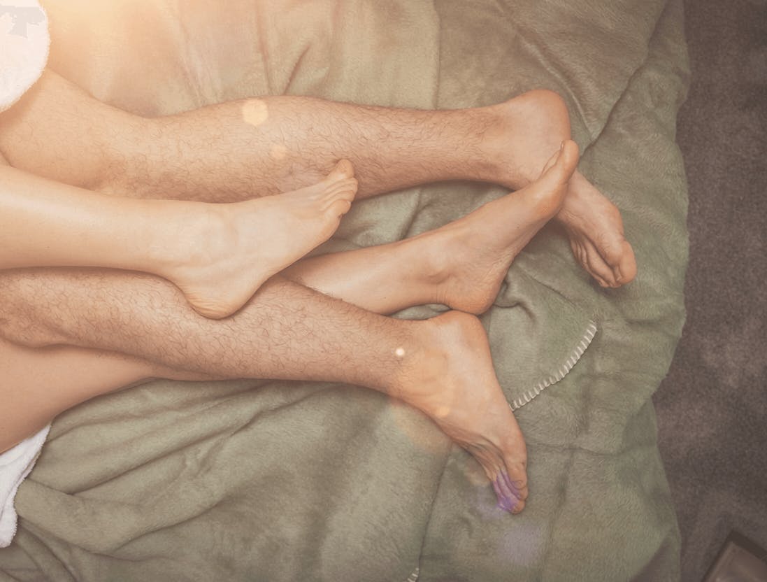 Die Füße eines Paares beim Kuscheln auf einer Decke.